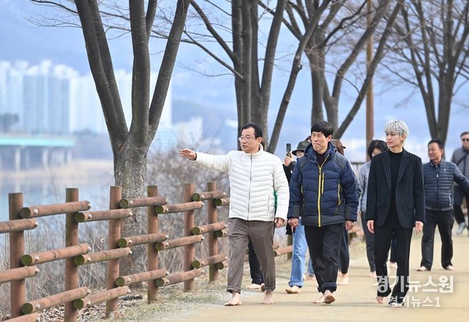 이현재 하남시장이 보이그룹 아이콘(iKON) 멤버 송윤형씨와 함께 한강 제방 모랫길을 맨발로 걸으며 점검하고 있다.