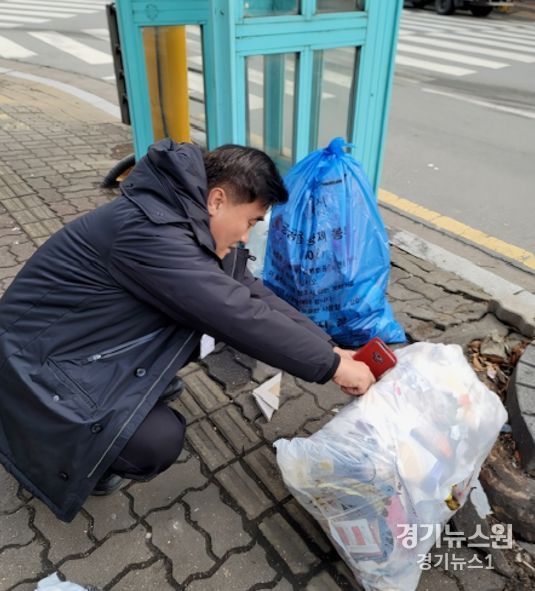 수원시 깨끗한 쓰레기처리 감시원이 무단 배출된 생활폐기물을 살펴보고 있다.