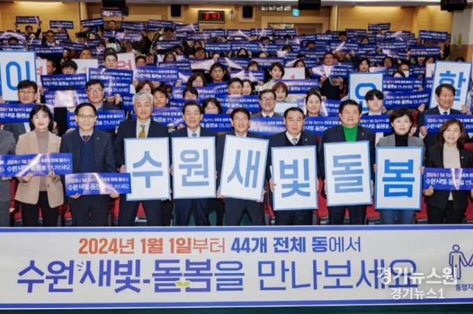 지난해 12월 수원시 관계자들이 수원새빛돌봄 전체 동 확대를 홍보하는 손팻말을 들어 보이고 있다.