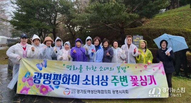 광명시 여성단체협의회가 10일 광명동굴 입구에 설치된 평화의 소녀상 주변에 봄꽃 300그루를 심고 기념사진을 촬영하고 있다.